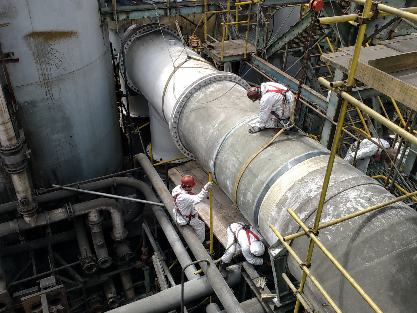 Trabajadores realizando labores sobre un ducto industrial en terreno.